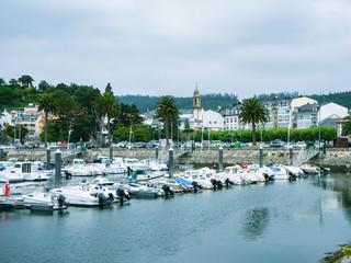 Paisaje marino con barcas y el campanario en el fondo en el pueblo de Ortigueira en La Coruña,...