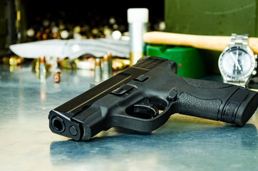 Compact 9mm pistol laying on table with ammunition and gunsmith tools in background