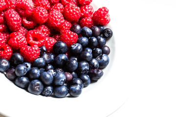 Raspberries and blueberries on white isolated background. Conceptual layout for your text. 