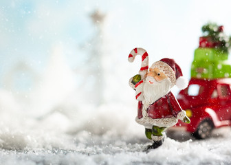 Santa Claus and red toy car carrying Christmas gifts in snowy landscape.