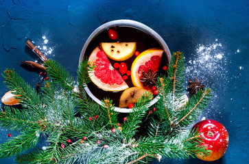 Christmas background. Hot mulled wine with ingredients in authentic ladle on blue concrete...
