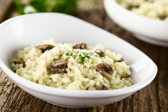 Fresh homemade mushroom risotto with parsley in white bowl (Selective Focus, Focus on the two mushroom pieces in the front)