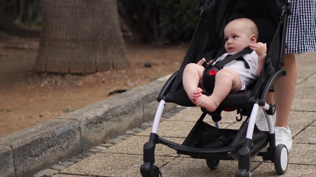 Rear view of young mother sitting at the beach with baby stroller