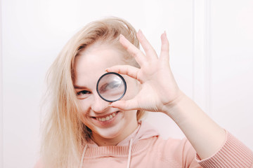  Cute girl with a magnifying lens on the eye. concept of the curvature of reality.