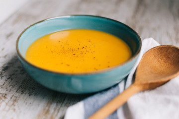 Pumpkin soup in a blue bowl in a wooden table