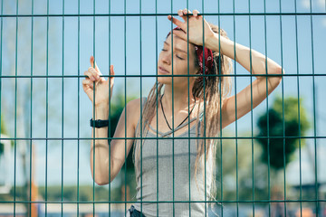 Beautiful long haired lady standing with her eyes closed and leaning on the fence