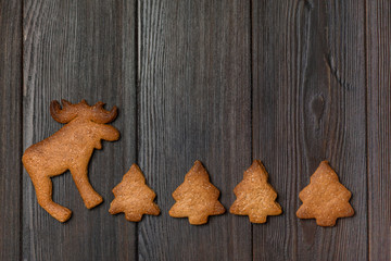 Christmas background with festive figures a ginger biscuit on a dark wood background. Place for writing. Winter layout