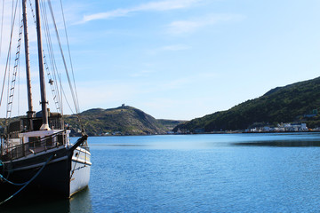 Panoramic view of St. John's Harbour with a sailboat moored at the dock in the foreground and Signal Hill in the background. 