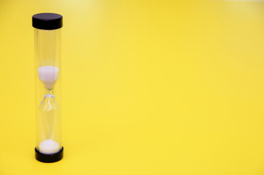 Playing Hourglass With White Sand Inside On Yellow Background