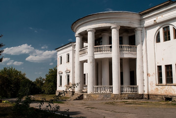 Facade of an old building with columns against the sky and clouds