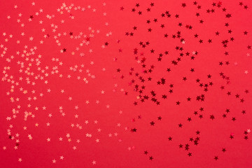 Beautiful festive red background with metallic star shaped confetti. Holiday or decoration concept.