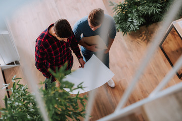 Top view of young men are planning of construction object while standing in office