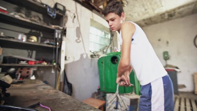 Teenage boy carrying heavy tool box in a workshop