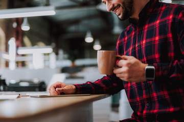 Joyful handsome man sitting at the table and drinking tea in the office