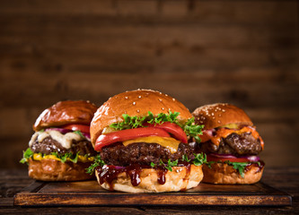 Tasty burgers on wooden table.