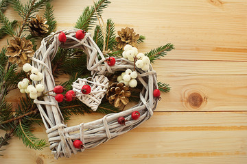 Christmas heart wreath with winter berries and branches of a Christmas tree on a wooden background
