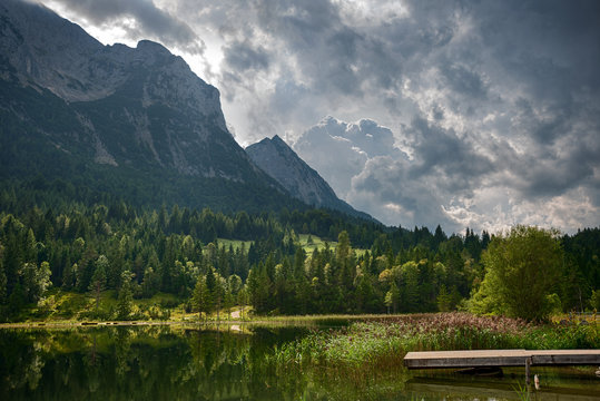 Sunlit gangway at Ferchensee lake, Germany. Thunder clouds