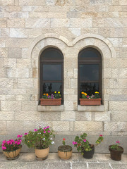 Fototapeta na wymiar Home exterior with window decorated by flowers and reflections of people at Kruja, Albania