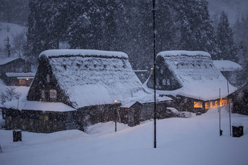 Large traditional Japanese gassho-zukuri mountain houses in heavy snow as night falls
