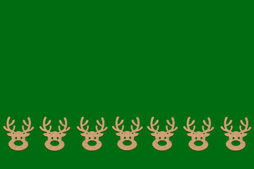 Obraz na płótnie Canvas Wooden Christmas toys head of a deer is lined with a pattern on bottom side on a green background. Add text Merry Christmas and Happy New Year. Minimalistic style. Flat lay, top view