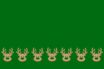 Wooden Christmas toys head of a deer is lined with a pattern on bottom side on a green background. Add text Merry Christmas and Happy New Year. Minimalistic style. Flat lay, top view