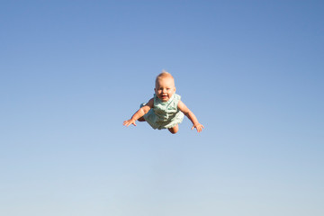 Flying child with a happy face against the blue sky. Concept game with children, happy family