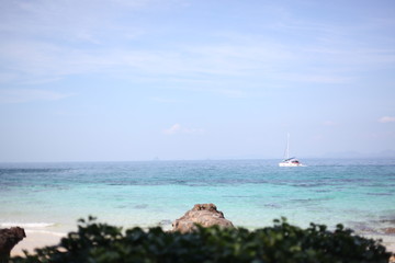 Fototapeta na wymiar yacht goes by the sea, blue sky, sandy beach.