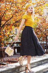 Outdoor full body fashion portrait of young beautiful happy smiling girl wearing yellow beret,...