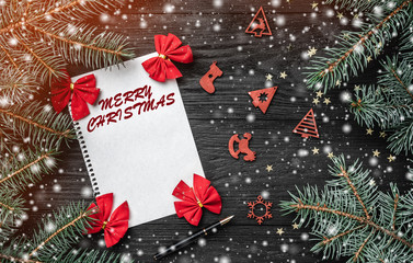 Fir branches and red bowls, on black wood background. Xmas greeting card. Space for your text. Christmas toys. Top view. Snow and light effect