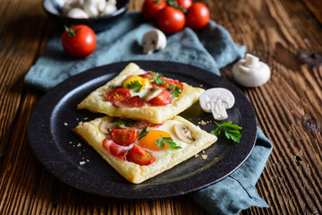 Fototapeta na wymiar Puff pastry pies with egg, bacon, mushrooms and tomato