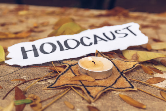 Inscription Holocaust. Star of David and candle on autumn leaves