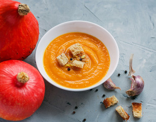 Pumpkin soup and organic pumpkins, top view, copy space. Seasonal autumn food - Spicy pumpkin soup with croutons and pumpkin seeds.