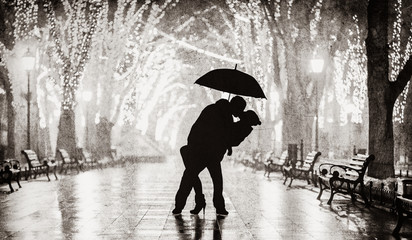 Couple with umbrella kissing at night alley. Image in back and white color style