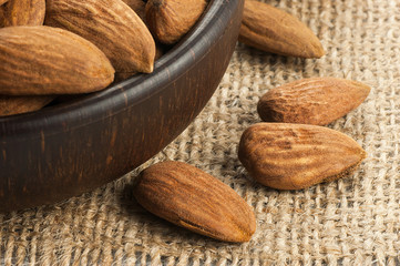 Almonds nuts in dark Brown bowl on  burlap sack. Almond background concept with copy space
