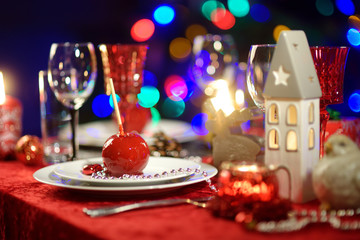 Beautiful table setting for Christmas party or New Year celebration at home. Cozy room with a fireplace and Christmas tree in a background.