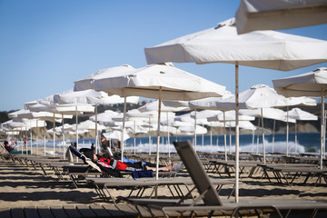 Fototapeta na wymiar Tourists enjoy the last warm days, during off-season in late autumn, on a Black Sea beach