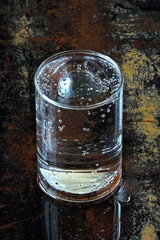 A glass of clean drinking water on a shabby rusty surface.