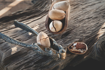 Pecan and macadamia nuts with a device for chopping nuts on a wooden background