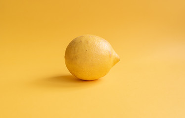 Closeup of natural looking lemon on yellow background (selective focus)