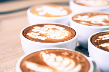 fresh cups of coffee latte arts serve on the wooden table in the vintage style cafe