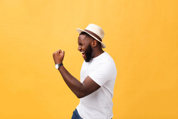 Handsome young Afro-American man employee feeling excited, gesturing actively, keeping fists clenched, exclaiming joyfully with mouth wide opened, happy with good luck or promotion at work