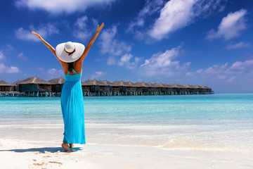Attraktive Frau in blauem Sommerkleid läuft an einem tropischen Strand und ist glücklich
