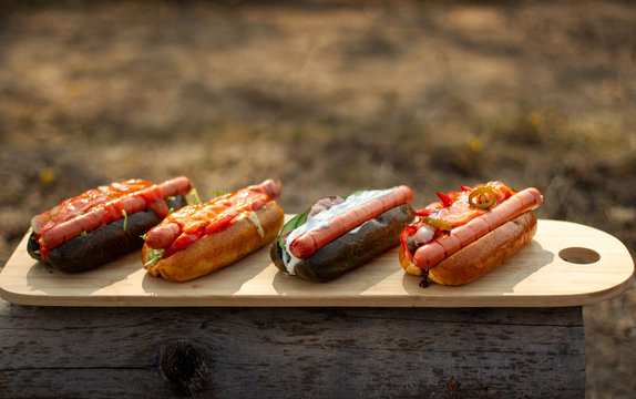 Hot dogs lie in the sun on the wooden plate.