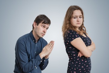 Young man is begging for forgiveness young angry woman.