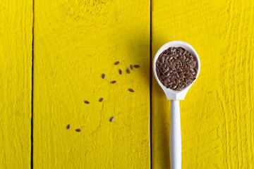 wooden spoon with flax seeds on a yellow rustic table