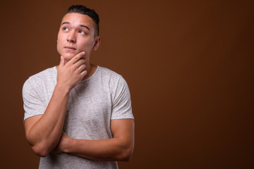 Young handsome multi-ethnic man against brown background