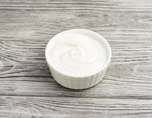 bowl of sour cream yogurt on gray wooden background.