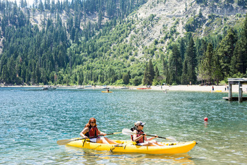 Two female friends row in a dual kayak on Lake Tahoe in Emerald Bay. Concept for teamwork, female...