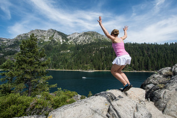 Young woman jumps off a rock on Fannette Island in Lake Tahoe California. Concept for leap of...