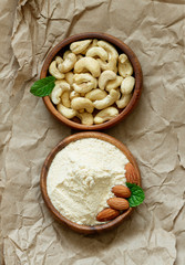 Bowls of cashews and almond flour on brown paper.